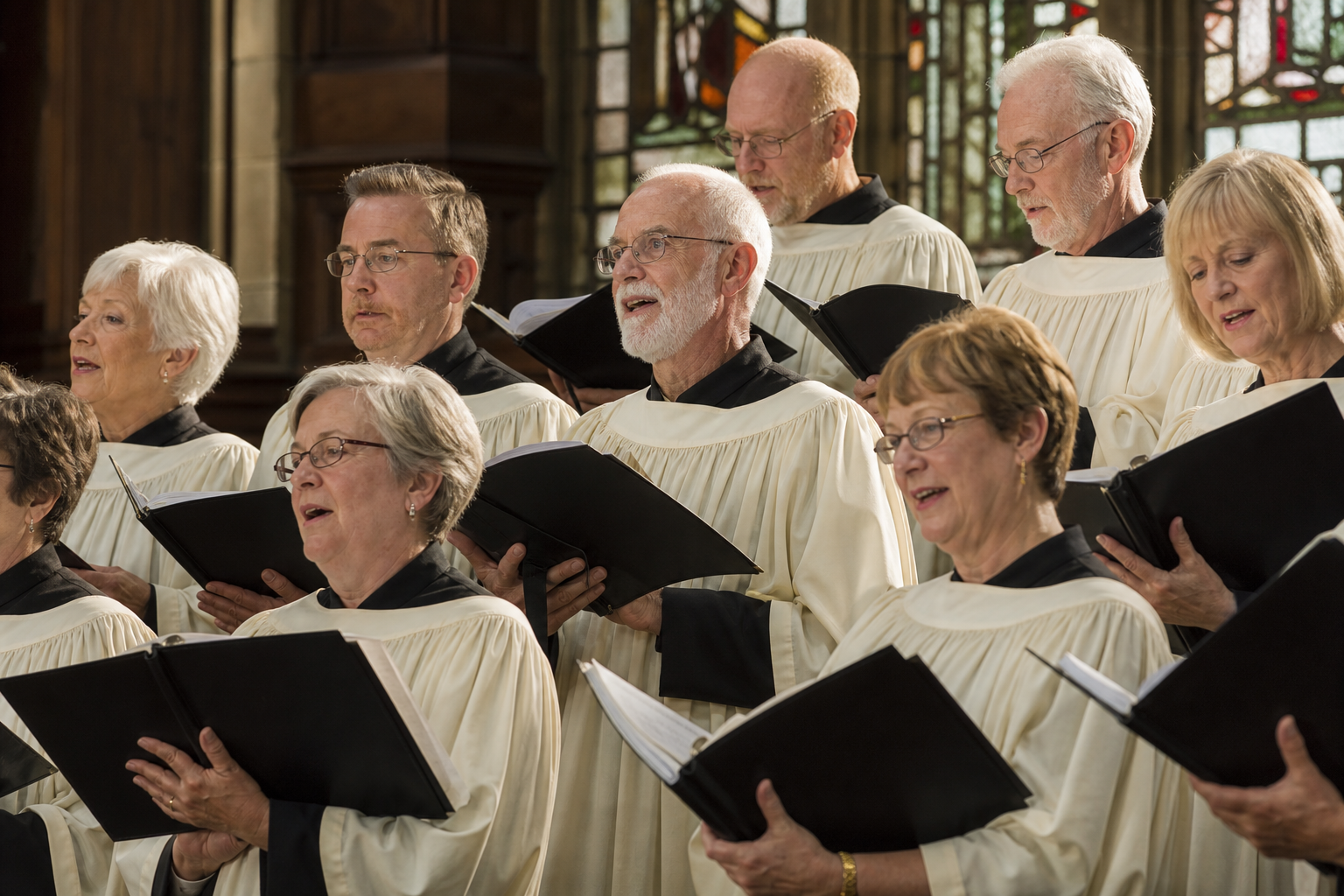 Ältere Sängerinnen und Sänger in einem hellen Kirchenchor, konzentriert und zugewandt